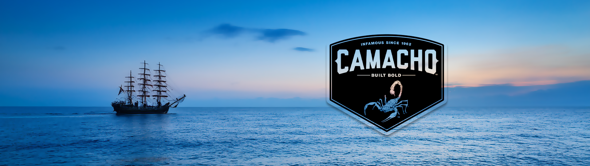 Silhouette of a tall sailing ship on a peaceful ocean at sunset with colorful sky, featuring the Camacho logo overlay.