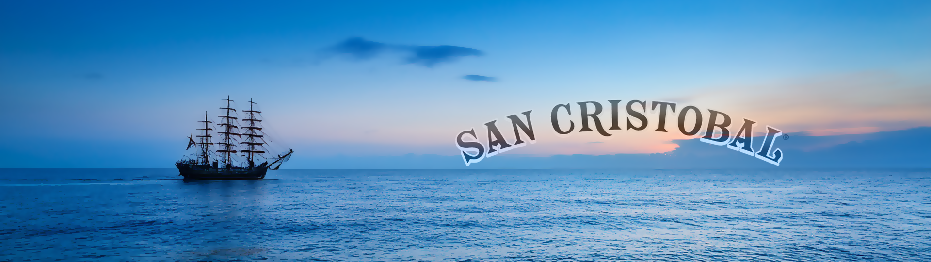 Silhouette of a tall sailing ship on a peaceful ocean at sunset with colorful sky, featuring the San Cristobal logo overlay.