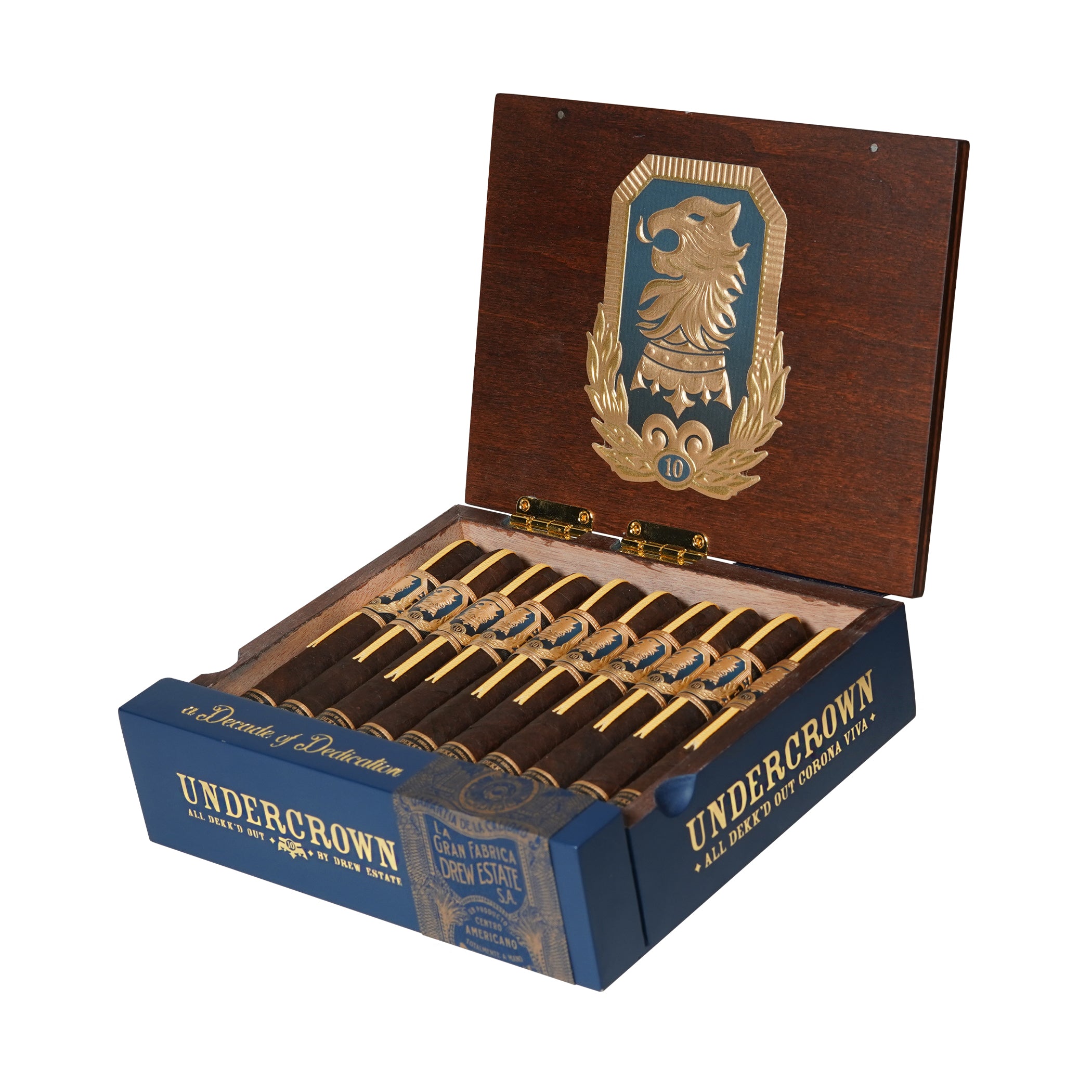 A wooden cigar box with a hinged lid, open to reveal a row of dark cigars with yellow and gold bands. The lid features an ornate emblem with a lion's head and number 10 in gold against a blue and brown background. The box is labeled "UNDERCROWN" in large gold letters on the front sides, with additional text reading "A Decade of Dedication," "Corona Viva," and "Gran Fabrica Drew Estate" in a vintage design. The cigars are neatly arranged.